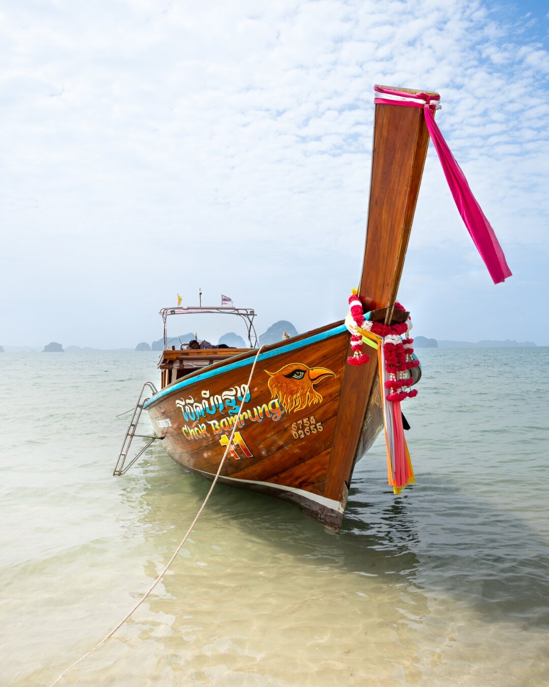 Decorated longtail boat Chok Bamrung with garlands in shallow turquoise water, Thailand — travel photography